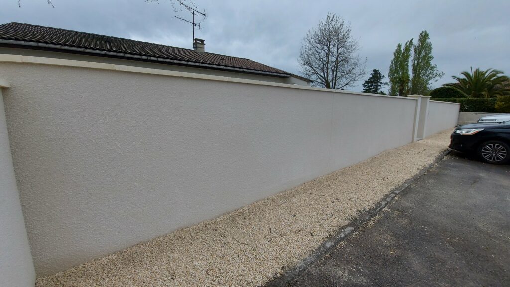 Travaux de petite maçonnerie : Clôture en mur plein finition enduit gratté ton pierre